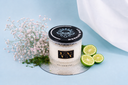 Candle labeled 'Morning Mist' with a black lid, surrounded by flowers and citrus on a light blue background.