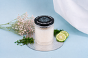 Candle labeled 'Morning Mist' with a black lid, surrounded by flowers and citrus on a light blue background.