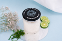 Candle labeled 'Morning Mist' with a black lid, surrounded by flowers and citrus on a light blue background.