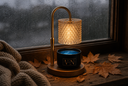 A warm, glowing table lamp with a textured cylindrical shade and a wood base sits on a wooden windowsill with a Velvet Noble wickless candle underneath the warm light.