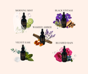 5 Velvet Drops bottles with fragrance names and matching fragrance visuals. Morning Mist, Black Vintage, Washed Amber, Velvet Ease, & Blushed Rain.