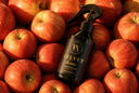A dark spray bottle labeled 'VN Velvet Home' placed on top of a dense pile of red apples.