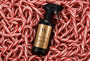 A black spray bottle of Velvet Sparkle holiday-themed all-purpose cleaner with a gold label, placed on a bed of red and white striped candy canes. The brand logo 'VN' is visible on the label.
