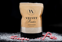 A stand-up pouch of Velvet Powder luxury freshener by The Velvet Noble, styled on a black background with white sugar-like powder scattered around and red-and-white striped candy canes in front.