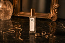 Velvet Stacks Mini Air & Linen Mist with gold cap on a dark surface with jewelry