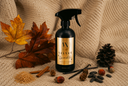 A black spray bottle labeled 'VN Velvet Sparkle' is styled on a beige knit blanket with autumn leaves, cinnamon sticks, sugar, pinecones, vanilla beans, and acorns.
