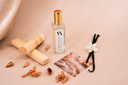 Mini Air & Linen mist with vanilla beans, flowers, and a wooden stick on a beige background