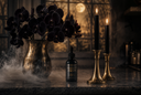 A small dark amber bottle labeled 'VELVET DROPS' sits on a tabletop beside a metallic vase of black orchids, two lit black candles in gold holders, and mist in a moody interior setting.
