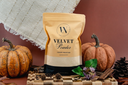 A stand-up pouch of Velvet Powder luxury carpet powder by The Velvet Noble, styled on a wooden board with pumpkins, pinecones, and a rustic woven textile against a warm brown background.
